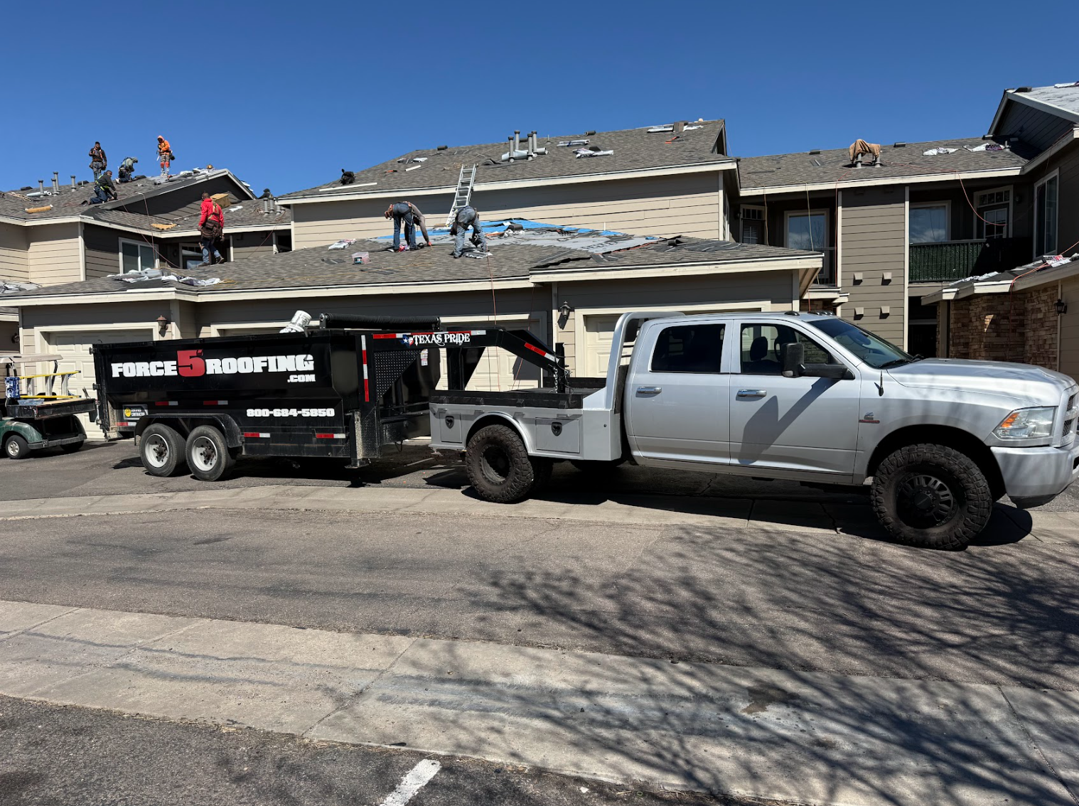 Force 5 Roofing crew on a Denver-area job site with branded truck and dump trailer