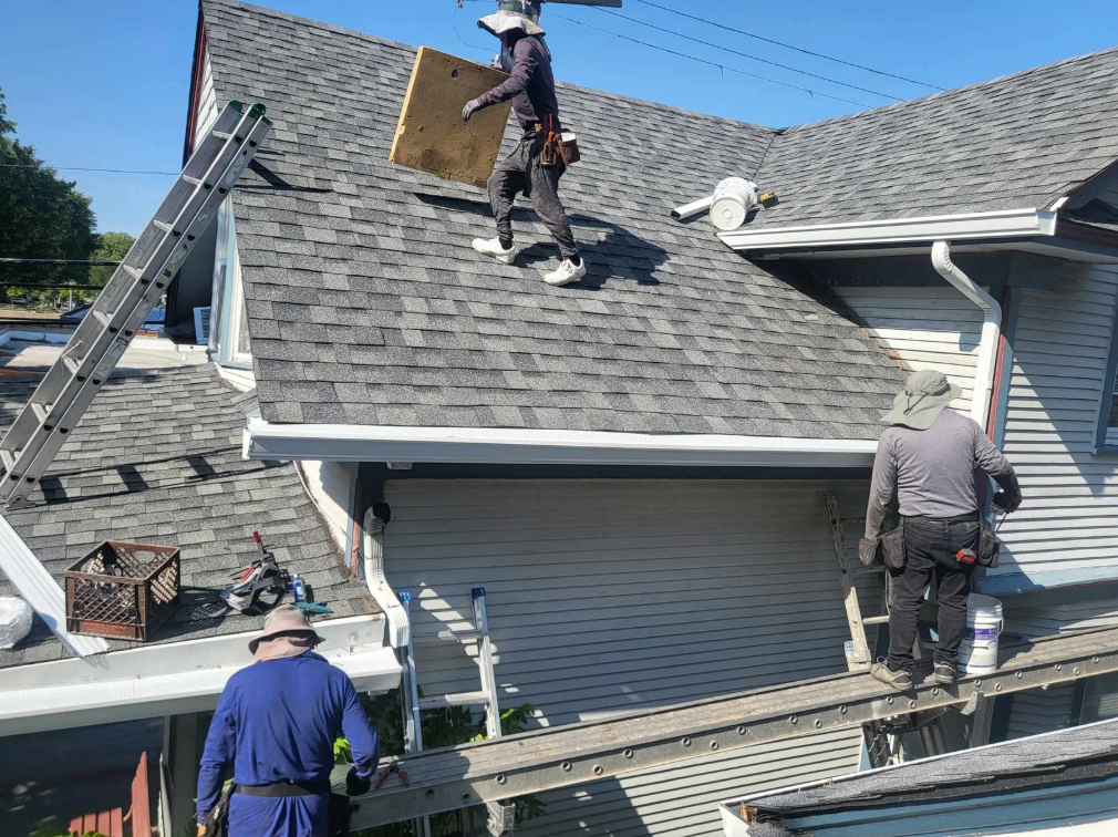 Force 5 Roofing crew installing seamless gutters on a residential home — crew on the roof and on ladders working together to hang a new run