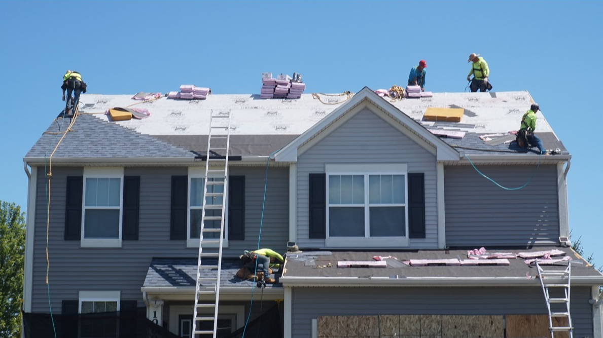 Force 5 Roofing crew installing a new roof on a two-story Denver Metro home, with new shingle bundles staged on the deck