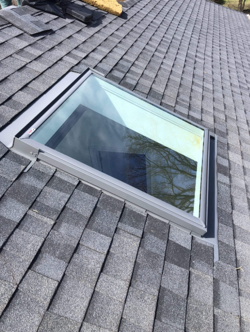 Force 5 Roofing newly installed skylight with fresh metal step flashing tying into the shingle field — clean watertight detail on a residential roof